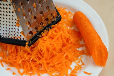 Beyaz bir tabakta taze çiğ rendelenmiş havuç. Sağlıklı beslenme ve vejetaryen gıda.