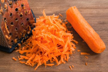 Kahverengi ahşap arka plan üzerinde taze çiğ rendelenmiş havuç.