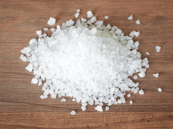 Montón de sal marina comestible con cristales grandes en una tabla de cortar de madera marrón — Foto de Stock