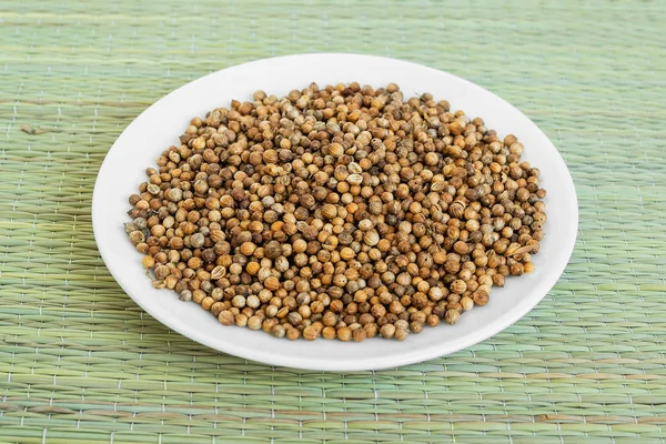 Yeşil bir masa mat üzerinde beyaz bir tabak üzerinde kişniş tohumu bir sürü 