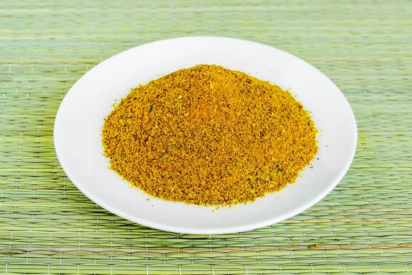 Un montón de polvo de curry en un platillo blanco en una alfombra de mesa verde —  Fotos de Stock