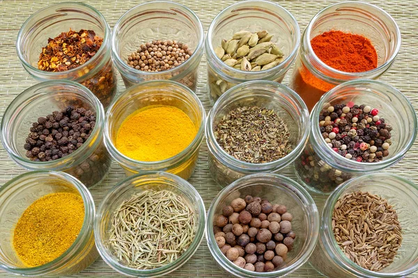 Twelve different spices and herb seasonings in a glass jars