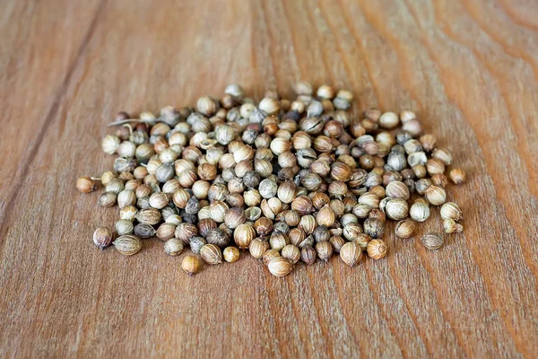 Tas de graines de coriandre sur une planche à découper en bois brun . — Photo