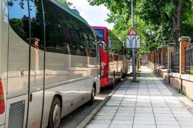 Güneşli bir yaz gününde bir şehir caddesinde üç modern turist otobüsleri