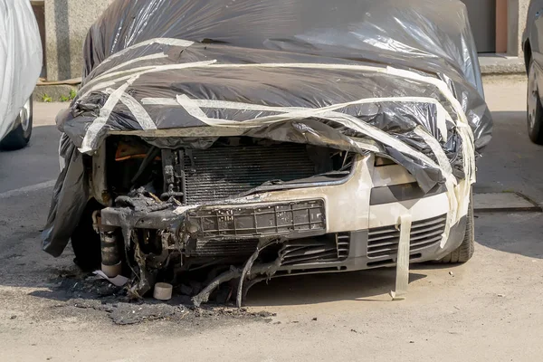 Car damaged by fire. Partially burnt cars covered with a black film.