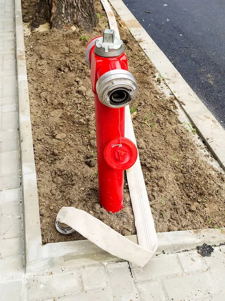 Hidratante de fogo vermelho com um selo aberto e uma longa mangueira de fogo branca — Fotografia de Stock