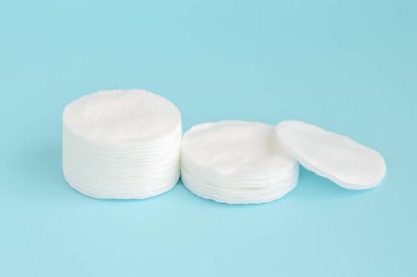 Mavi arka plan üzerinde yığılmış yuvarlak pamuk pedleri. Hijyen malzemeleri.