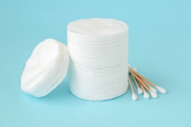 Yığılmış yuvarlak pamuk pedleri ve ahşap sopa pamuk tomurcukları yığını mavi