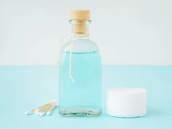Tonic for face skin or makeup remover in a glass bottle,  cotton pads and wooden cotton buds