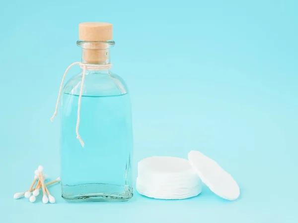 Tonic for face skin or makeup remover in a glass bottle, cotton pads and wooden cotton buds