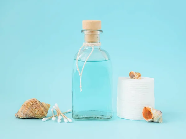 Tonic for face skin or makeup remover in a glass bottle, cotton pads, wooden cotton buds and few sea shells