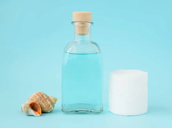 Tonic for face skin or makeup remover in a glass bottle, cotton pads and sea shell