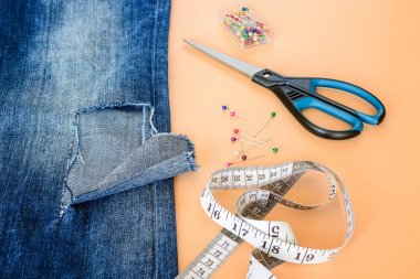 Bir pantolon bacak üzerinde büyük bir delik ile Mavi kot, dikiş pimleri, terzi bant ve makas