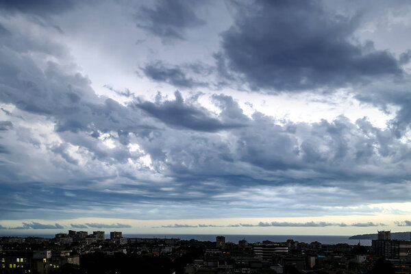 Dark stormy sky over a seaside city at summer evening. Dramatic skyscape.