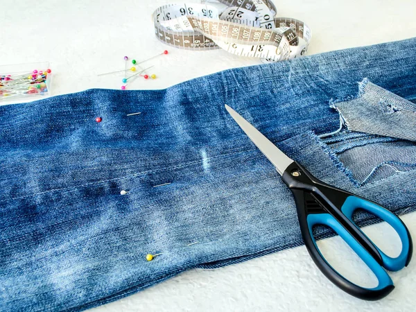 Blue jeans with large hole folded in half. Shorten the jeans. — Stock Photo, Image