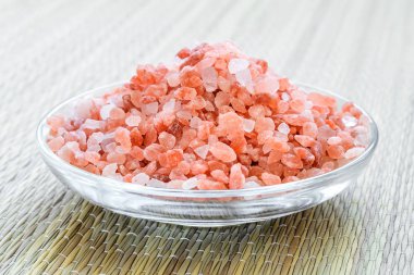 Bir cam tabak pembe himalaya tuzu kristalleri yığını.