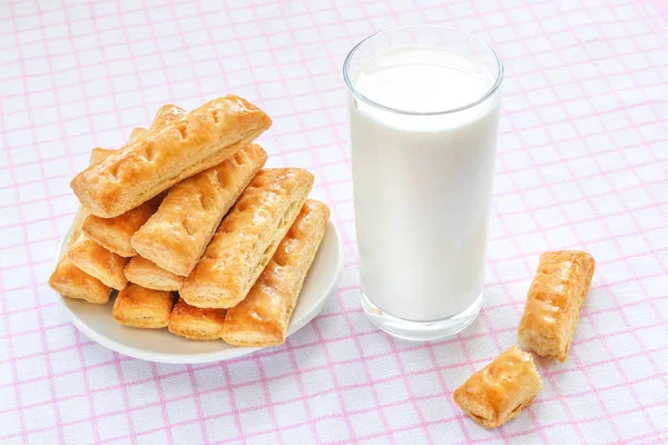 Sweet puff pastry cookies on a white saucer and glass of milk — Stock Photo, Image