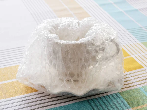 White elegant tea cup and saucer fully packaged with bubble wrap — Stock Photo, Image