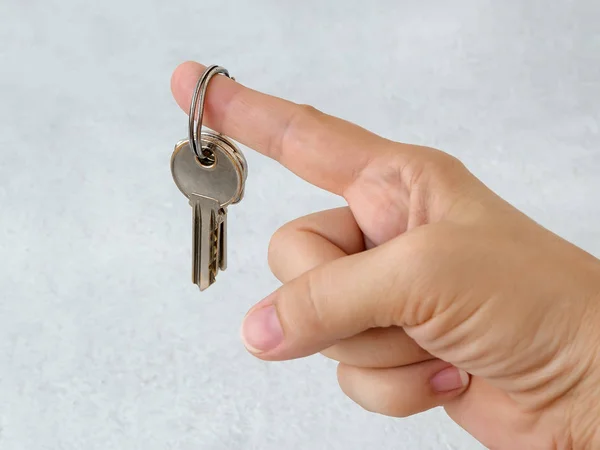Куча ключей от дома на кольце, висящем на указательном пальце — стоковое фото