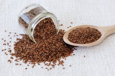 Düşmüş cam kavanoz ve beyaz bir bütün keten tohumu ile ahşap kaşık