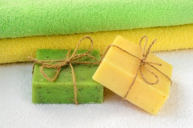 Yeşil ve sarı el yapımı sabun çubukları ve havlular.