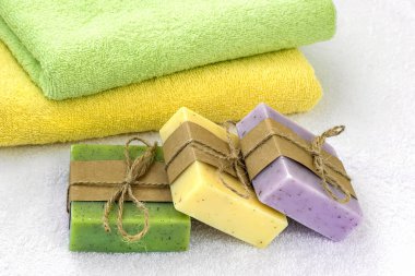 Yeşil, sarı ve mor el yapımı sabun çubukları ve havlular.
