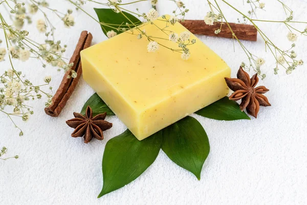 Yellow handmade soap bar on a green leaves over terry towel.