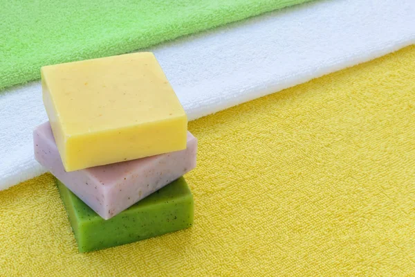 Stoh zelených, fialových a žlutých ručně dělené mýdlové tyčinky na froté ručníky. — Stock fotografie