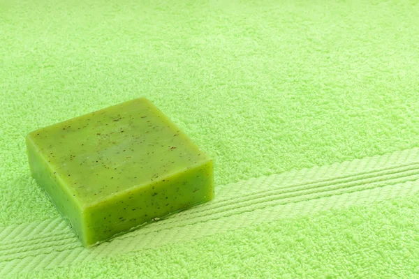 Green soap bar with aromatic herbs on a green terry cotton towel