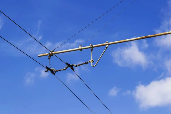 Contact wires of a trolley bus against a blue sky with clouds. — ストック写真