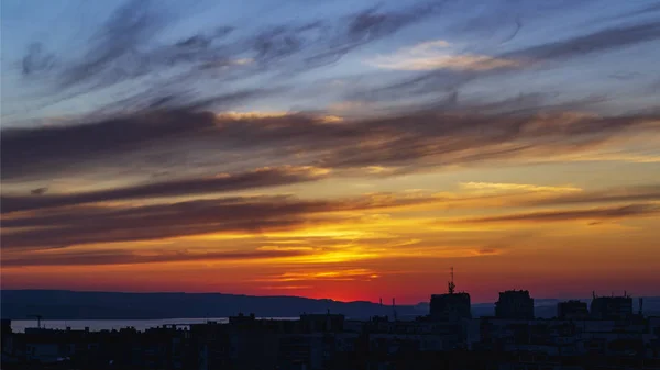 Escénica puesta de sol resplandor sobre una ciudad. Cielo vivo durante la puesta del sol . — Foto de Stock