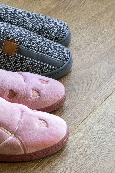 Two pairs of home slippers: gray mens and pink womens on a floor — Stock Photo, Image