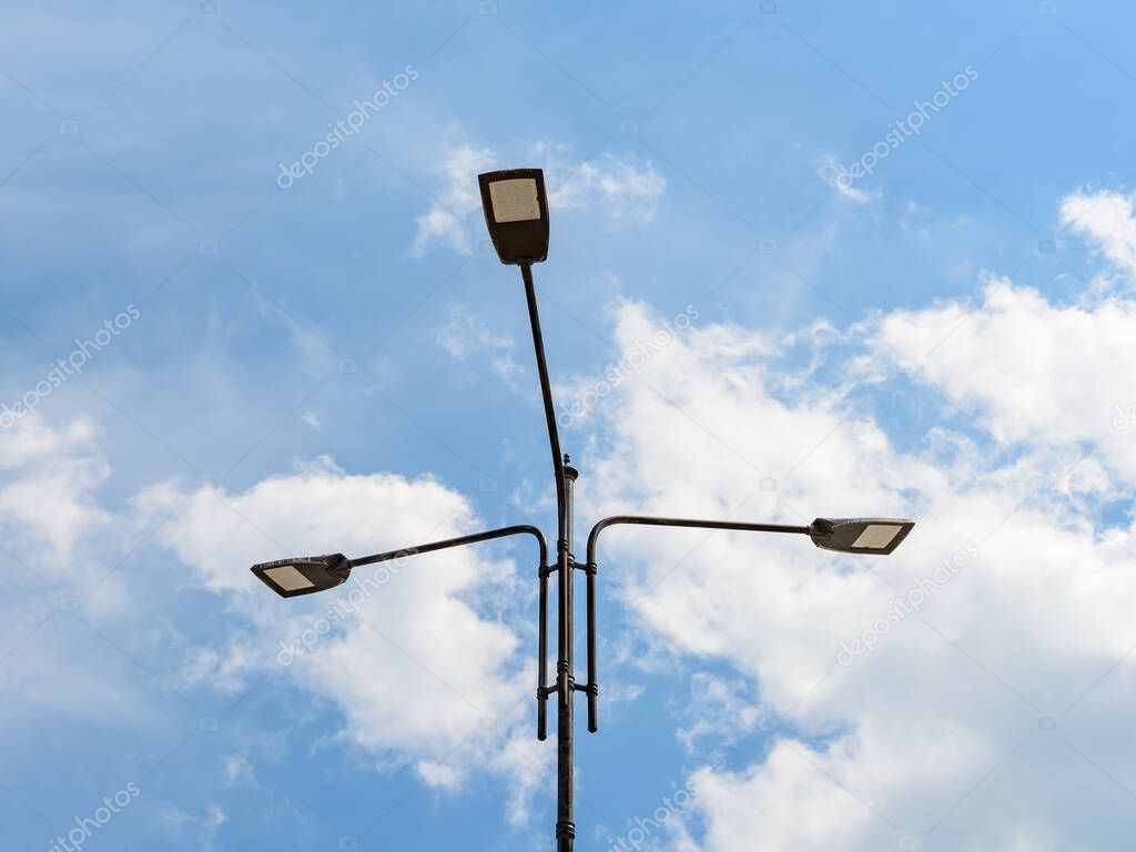Three led street lights on a pole against blue sky with light clouds. Modern energy-saving technologies for lighting streets and roads. Led street lamps. Low angle view.