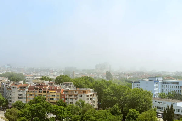 Dense fog on a sunny summer day in Varna. Thick fog came from the sea and covered the city. Climate and weather changes. High angle view.