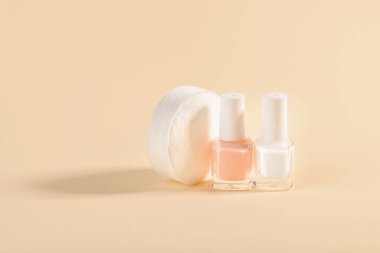 White and pale pink nail polish and cotton pads on a powdery color background. Manicure, pedicure, nail care products. Copy space. Front view. clipart