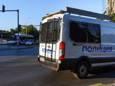 Varna, Bulgaristan, 18 Temmuz 2020. Tutukluları taşımak için kompartımanı olan beyaz polis minibüsü güneşli bir yaz gününde şehir caddesindeki kavşakta döner..