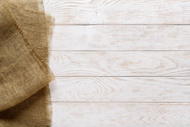 Beyaz boya ve kenarı doğal renk çuval bezi ile boyanmış, ahşap bir masa üstündeki alanı kopyala. Döşeme tahtalarından ve çuval bezinden oluşan boş bir yüzey. Üst görünüm.