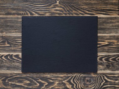 Siyah boyayla boyanmış ahşap bir masanın üzerine servis tahtası koyun. Menü ya da fiş tasarımı için bir model. Boş siyah yüzey. Üst görünüm.