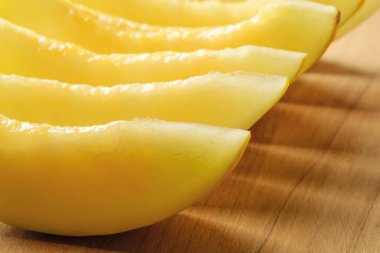 Kahverengi tahta kesme tahtasının üzerinde tatlı sulu kavun dilimleri. Tatlı meyveler ve meyveler. Vejetaryen, çiğ gıda diyeti ve sağlıklı beslenme. Yakın plan..