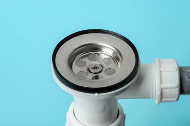 Yeni bir su tuzağına süzgeci yakın çekim ya da mavi arka planda lavabo drenajı. Beyaz pvc plastik ve paslanmaz çelikten yapılmış yerli tesisat tesisatlarını kurun, temizleyin ve tamir edin. Stüdyo çekimi. 