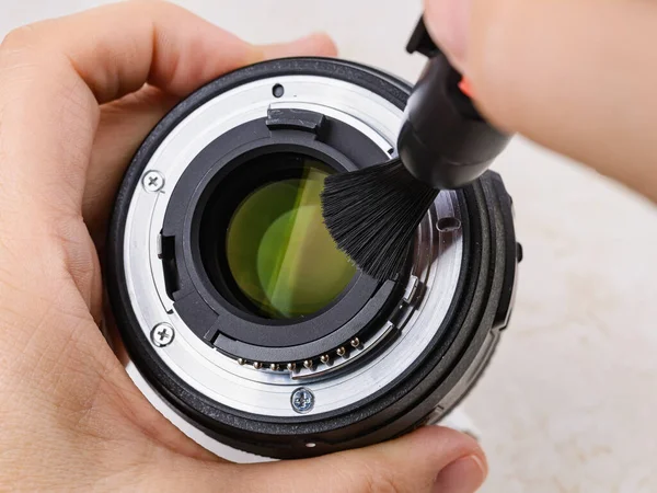 Lens fırçası kullanarak kamera merceğinin tozunu alan eller. Fotoğraf ekipmanlarından tozların ve parmak izlerinin rutin olarak alınması. Bakım ekibi yakın plan. Ön görünüm.