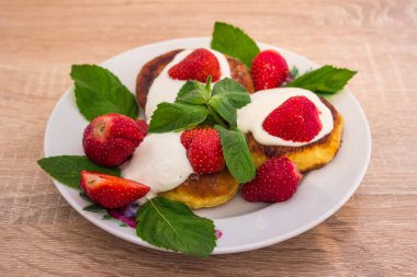 Bir tabağa Cheesecakes ekşi krema çilek ile yalan