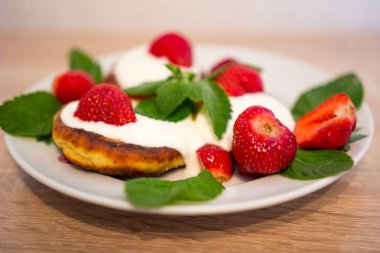 Bir tabağa Cheesecakes ekşi krema çilek ile yalan