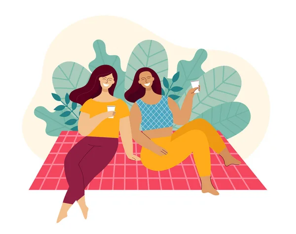 Δύο νεαρές γυναίκες κάθονται πάνω σε ένα καρό σε ένα πάρκο. Οι φίλοι γελάνε και μιλάνε. Έννοια του πικ-νικ, χαλάρωση το Σαββατοκύριακο. Καλάθι με φαγητό, καπέλο και μπάλα. Εικόνα διανύσματος επίπεδου χρώματος. — Διανυσματικό Αρχείο