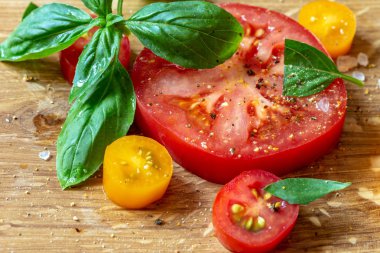 Bir ahşap tahta üzerine dilimlenmiş domates ve fesleğen.