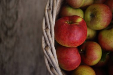 Tahta bir masanın üstünde elma dolu bir sepet.