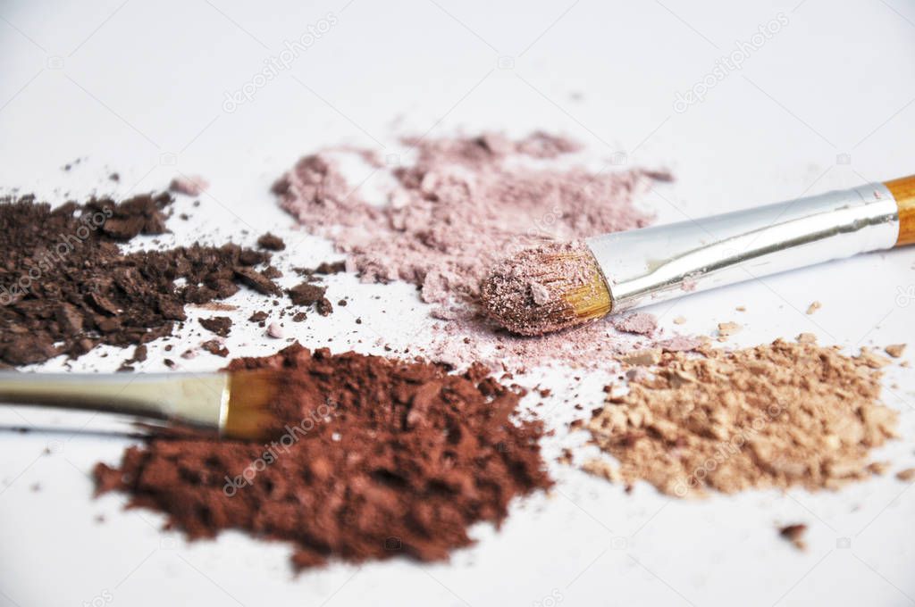 different colors piles of eyeshadows with brushes on white background 