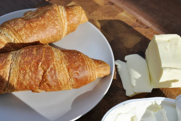 tasty croissant on a plate with butter and cream cheese