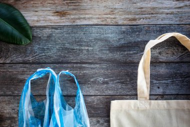 Bir plastik torba ahşap arka plan üzerinde düz yatıyordu, üst görünüm karşı Eko alışveriş çantası. Dünya gezegeni kurtarmak