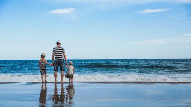 baba ve iki kızı sahilde ayakta, Akdeniz